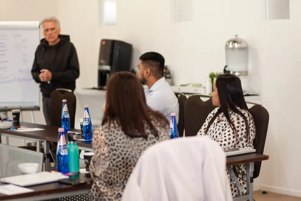 A Nexxt Group facilitator leading a workshop at a flipchart while participants follow from the table